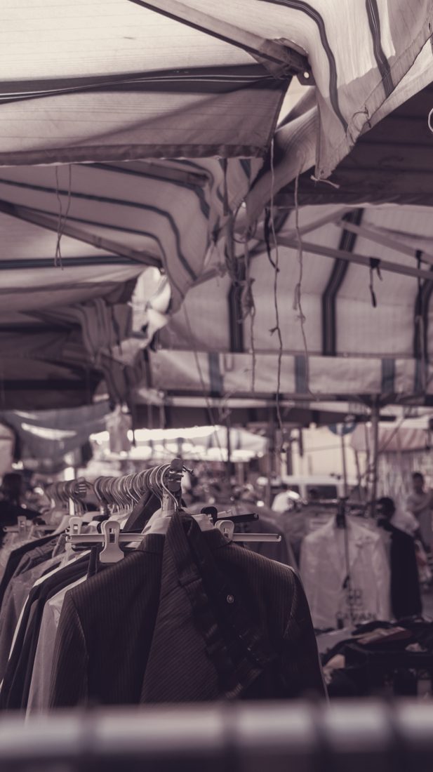 Shirts and jackets on hangers under a canopy at a market stall