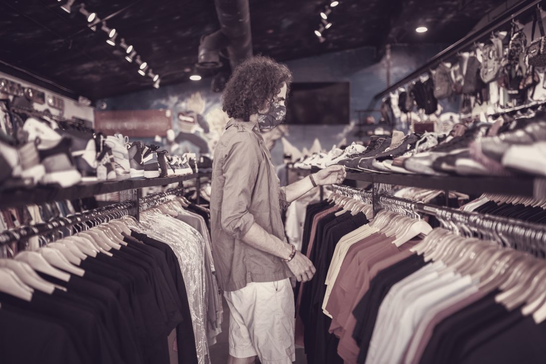 Shopper browsing a rail of shirts at a market
