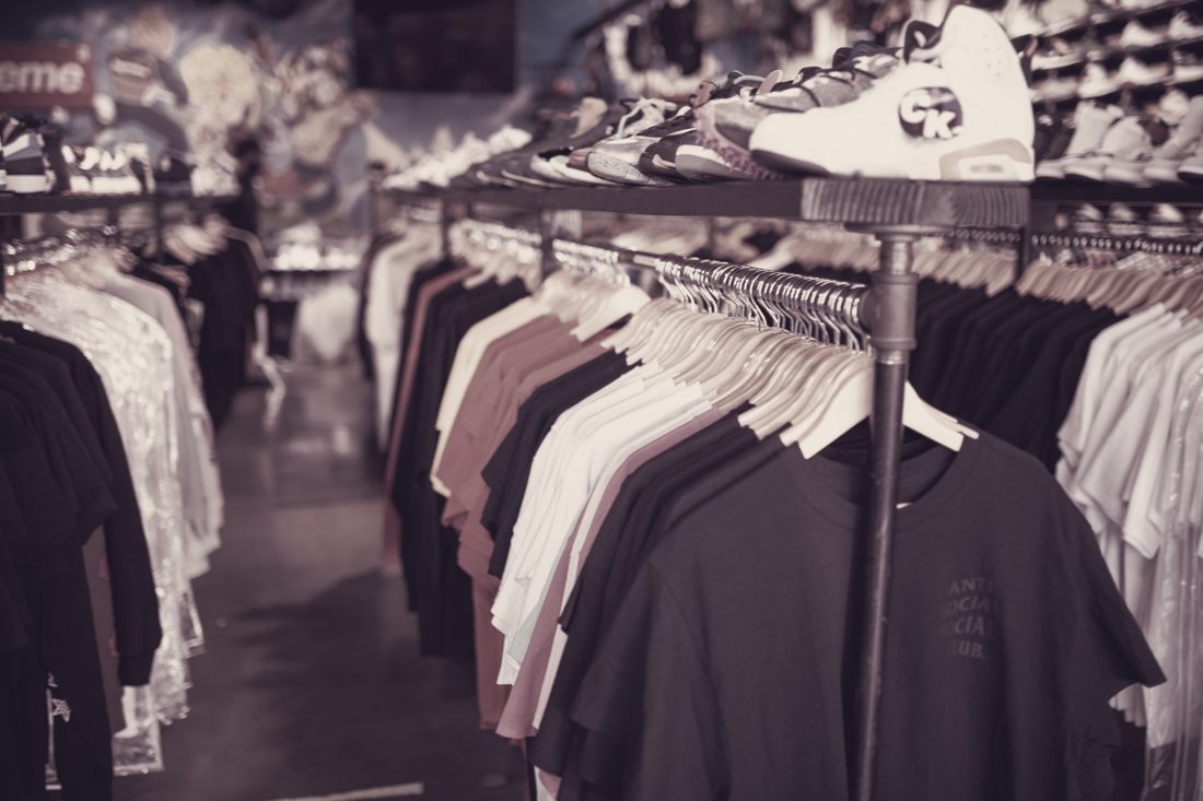 Market stall with T-shirts on rails and a sneaker on the shelf above — apparel and footwear